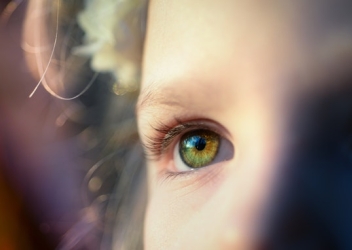 A child is pictured looking to the left of the image with a bright light showing their forehead and cheek in brighter fashion. 