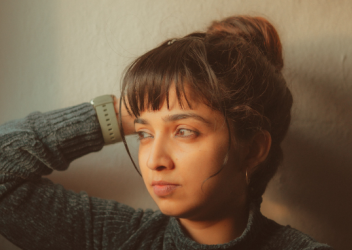 Teen female looking away from camera while holding right hand against side of her head