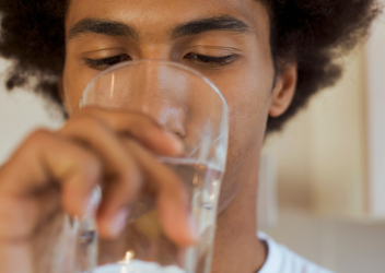 A teenager drinks from a glass 